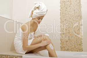 Woman applying moisturizer cream on the legs