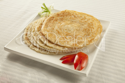 Plain paratha puri served with freshly sliced tomato and cucumbe