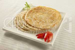 Plain paratha puri served with freshly sliced tomato and cucumbe