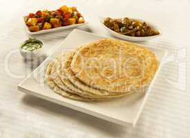 Paratha served with mixed vegetables, chutney and pickles