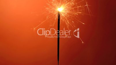 Burning sparkler on an orange background