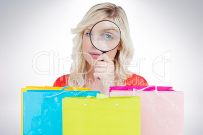 Composite image of fair-haired woman looking through a magnifyin