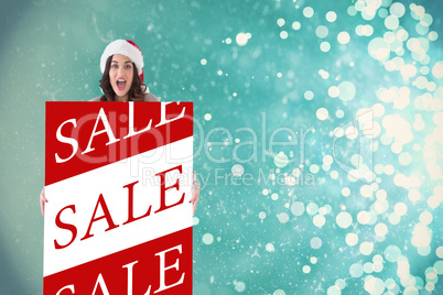 Composite image of happy brunette in santa hat showing white pos