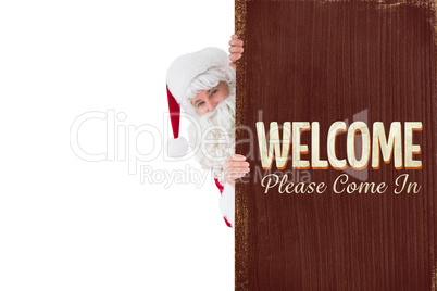 Composite image of smiling santa claus presenting sign