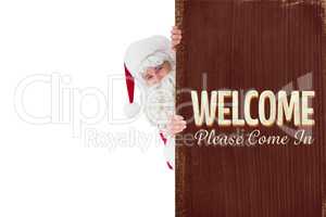 Composite image of smiling santa claus presenting sign