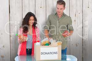 Composite image of volunteers taking out food from donations box