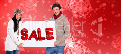 Composite image of young couple holding a poster