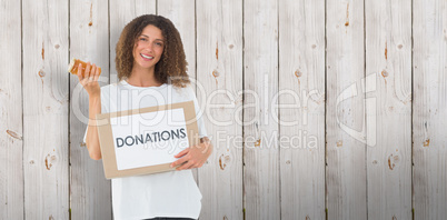 Composite image of happy volunteer holding a box of donations an