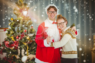 Composite image of geeky hipster in santa costume hugging his gi