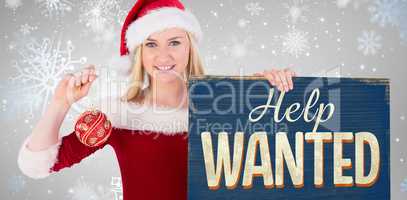 Composite image of festive cute blonde holding poster and bauble