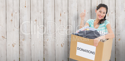 Composite image of woman with clothes donation gesturing thumbs