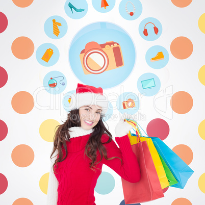 Composite image of festive brunette in winter wear holding shopp