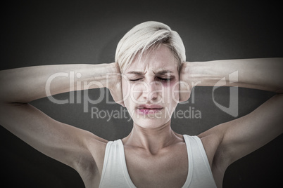 Composite image of upset woman covering her ears