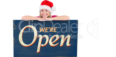 Composite image of festive blonde leaning on large poster