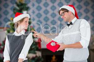 Composite image of geeky hipster offering present to his girlfri