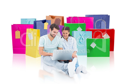 Composite image of cute couple sitting using the laptop