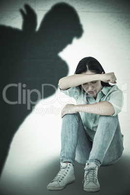 Composite image of sad woman sitting on the floor and hiding her