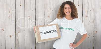 Composite image of smiling volunteer holding a box of donations