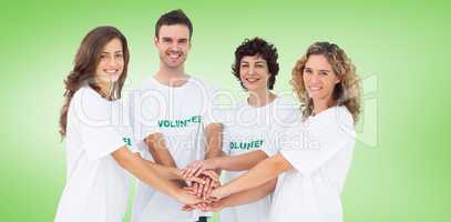 Composite image of smiling volunteer group piling up their hands