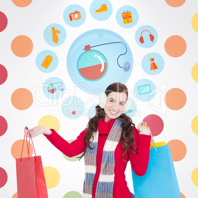 Composite image of brunette in winter clothes holding shopping b