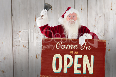 Composite image of santa holds a sign and rings his bell