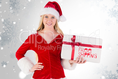 Composite image of festive blonde holding a gift