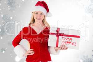 Composite image of festive blonde holding a gift