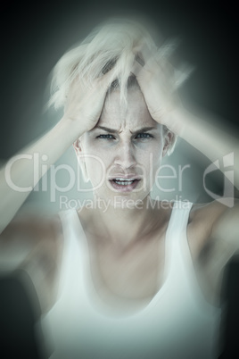 Composite image of sad blonde woman with head pain holding her h