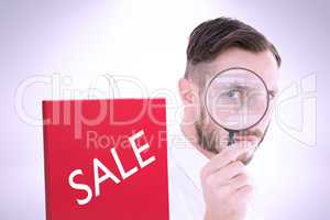 Composite image of geeky businessman looking through magnifying