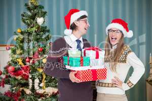 Composite image of geeky hipster couple holding presents