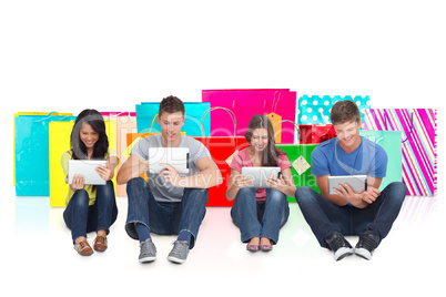 Composite image of four friends sitting on the ground all with t