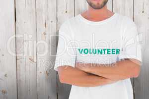 Composite image of man wearing volunteer tshirt with arms crosse