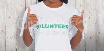 Composite image of woman wearing volunteer tshirt and giving thu