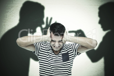 Composite image of frustrated man covering ears