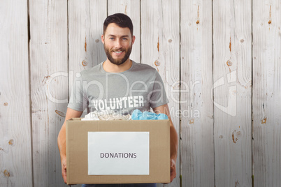 Composite image of portrait of man holding clothes donation box