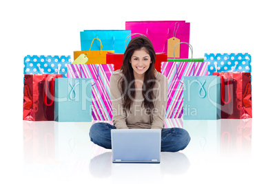 Composite image of woman sitting on the bed with the laptop in f