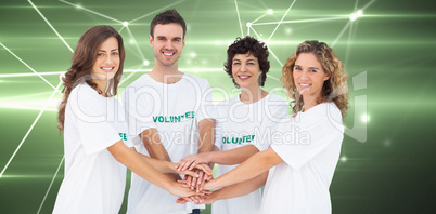 Composite image of smiling volunteer group piling up their hands