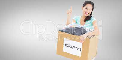 Composite image of woman with clothes donation gesturing thumbs