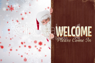 Composite image of smiling santa claus presenting sign