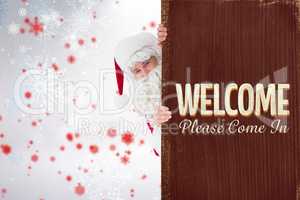 Composite image of smiling santa claus presenting sign