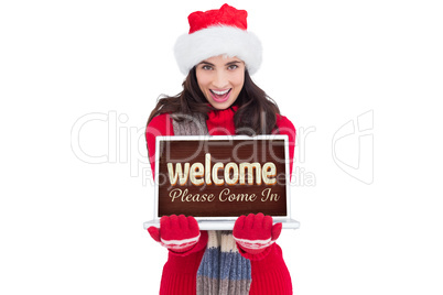 Composite image of festive brunette showing a laptop