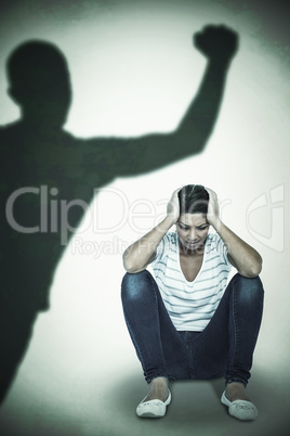 Composite image of depressed woman crouching on white background