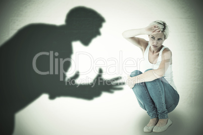 Composite image of crouching sad woman holding her hand