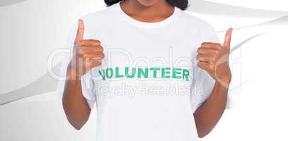Composite image of woman wearing volunteer tshirt and giving thu