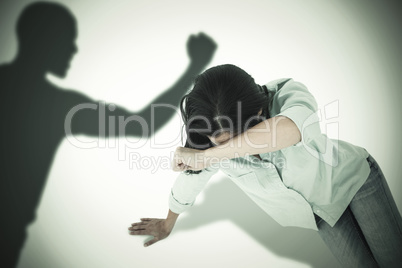 Composite image of sad woman sitting on the floor and hiding her