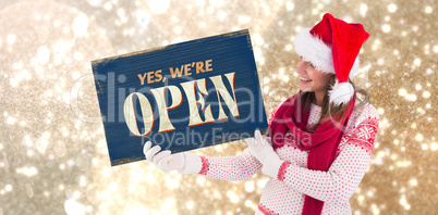 Composite image of festive brunette holding a poster