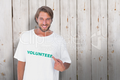 Composite image of smiling man pointing to his volunteer tshirt