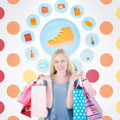 Composite image of pretty young blonde holding shopping bags