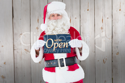 Composite image of smiling santa claus holding page
