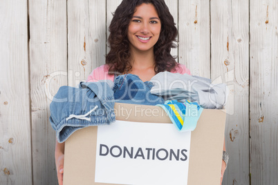 Composite image of volunteer holding clothes donation box